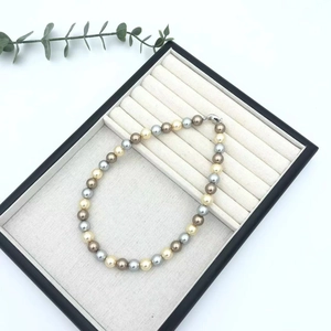 Multi-colored pearl necklace in champagne and bronze tones on a velvet tray