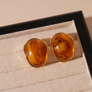 Detailed close-up of oval amber resin earrings with tortoise pattern and gold metal trim