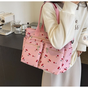 Close-up of pink cherry print tote bag with multiple zipper pockets and large capacity