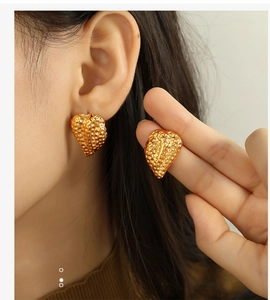 Détail de boucles d'oreilles vintage cœur torsadé doré avec texture gaufrée unique