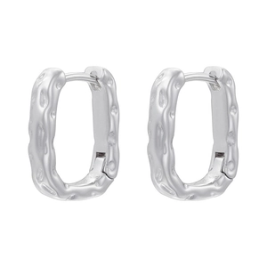 Détail de boucles d'oreilles rectangulaires argentées avec une texture en métal martelé
