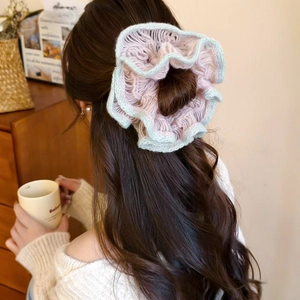 Detailed close-up of knitted floral scrunchie with pink and green ruffled textures