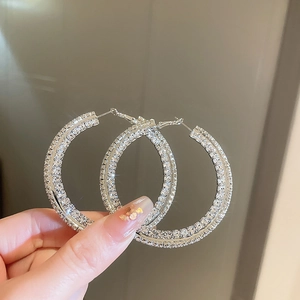 Detailed view of large silver hoop earrings with multiple rows of sparkling rhinestones