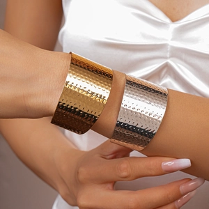Close-up of hammered metal cuff bracelets in gold and silver on a model wrist