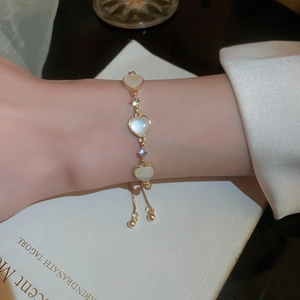 Elegant gold-plated bracelet with opal heart and pearls on a female wrist