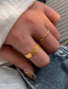 Detailed close-up of two stacked 18k gold plated rings with hammered and carved textures