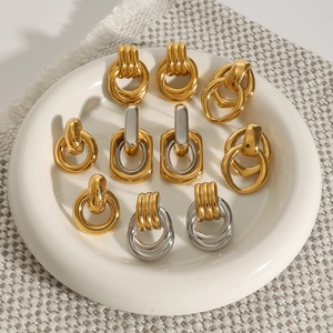 Macro shot of assorted gold and silver geometric hoop earrings on a ceramic dish