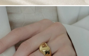 Polished gold heart ring worn by model over a beige blazer for a minimalist look