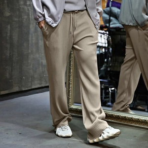 Detailed view of khaki ribbed knit trousers featuring loose straight fit and drawstring waist