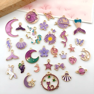 Macro shot of assorted purple enamel charms including moons, stars, and unicorns for DIY crafts