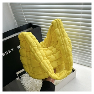 Detailed close-up of quilted puff bag in bright yellow featuring soft pleated texture
