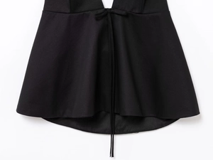 Détail d'un haut dos nu noir avec un élégant ourlet à nœud et un tissu d'armure lisse