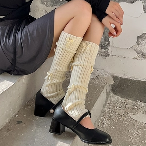 Détail de jambières en tricot crème avec nœuds et chaussures Mary Jane noires