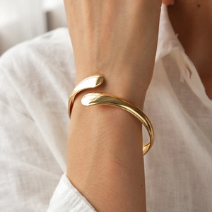 Close-up of golden geometric crossover cuff bracelet with a polished metallic finish