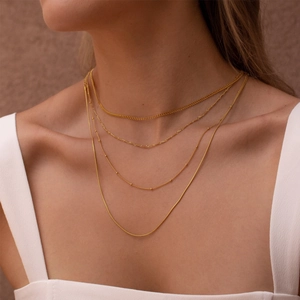 Close-up of layered gold-plated stainless steel necklaces with varied chain textures