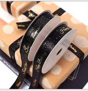 Detail of black satin ribbon with gold Happy Birthday foil print on gift box