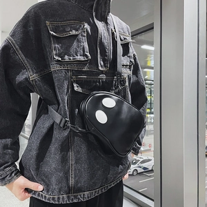 Street style view of a black ghost-themed PU crossbody bag with white oval eye detail