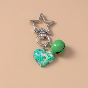 Detail of green resin heart keychain with iridescent sequins and small bell