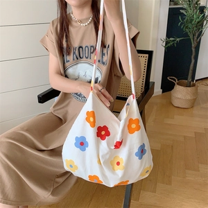 Lifestyle shot of large white canvas shoulder bag with colorful floral print and strap