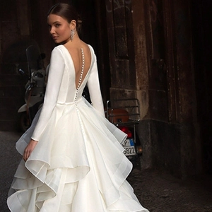 Detail of elegant backless wedding dress featuring long sleeves and pearl buttons