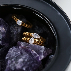 Macro detail of 18K gold-plated chain rings with square and pear-cut zircon stones