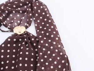 Détail du tissu en mousseline marron à pois avec une boucle métallique en forme de cœur