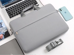 Detailed top view of grey canvas laptop bag with shoulder strap on white desk