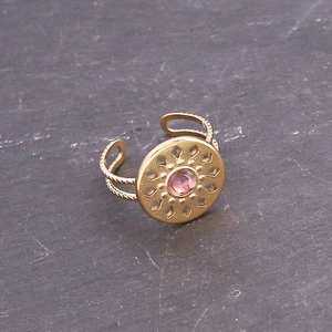 Detailed macro view of the open ring with pink stone inlay and ornate gold engraving