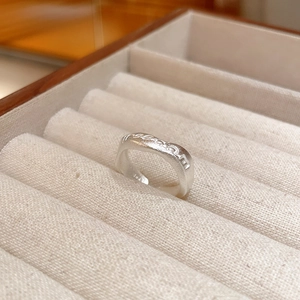 Macro shot of silver wavy ring with Freedom engraving and matte finish texture