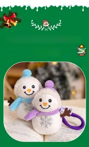 Detail of plush snowman pendants in blue and purple on a book with snowflake patterns