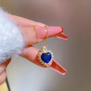 Close-up of heart-shaped blue sapphire pendant with crystal halo on gold chain
