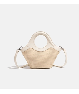 Detailed close-up of woven straw texture and premium white leather splicing on hand bag
