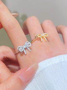 Macro view of bow rings with pavé micro-inlays in gold and silver finishes