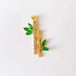 Macro shot of 18k gold bamboo pendant with green emerald stone and crystal accents