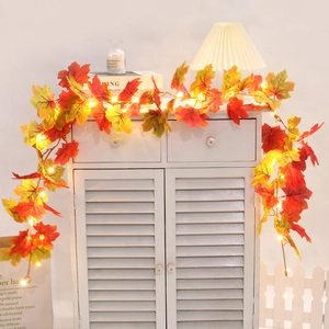 Close-up of autumn maple leaf garland with glowing warm yellow LED lights for home decor