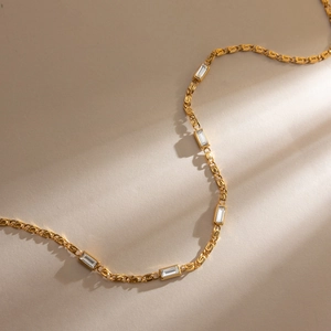 Classic 18K gold stainless steel necklace with rectangular rhinestones on warm sand