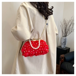 Détail du sac rouge à fleurs en dentelle avec poignée en perles et chaîne dorée