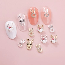 Detail of 3D cartoon bunny nail charms with pearls and rhinestones on pink background