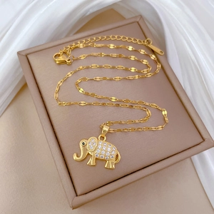 Macro view of crystal paved elephant pendant with gold lip chain on silk