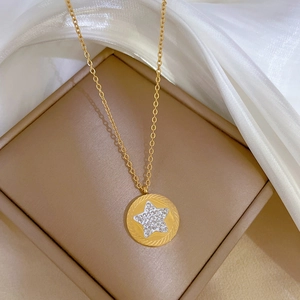 Detailed close-up of a gold star necklace pendant with crystal on white silk background