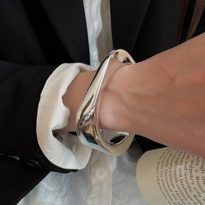 Detailed close-up of a high-polished irregular silver wide bangle with organic flowy shape