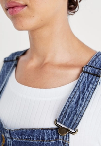 Detail of adjustable metal buckles and denim texture on casual women's overalls