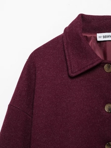 Detail of burgundy wool blend coat featuring notch lapels and dark resin buttons