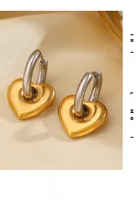 Détail de boucles d'oreilles pendantes en forme de cœur bicolores or et argent acier