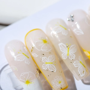 Stickers à ongles fleurs et papillons avec accents dorés et strass sur blanc laiteux