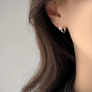 Close-up of silver zircon drop hoop earrings worn by a model in a minimalist style