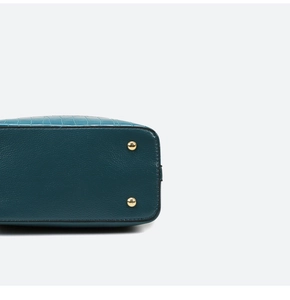 Detail of green faux leather bag with crocodile and lychee textures and gold feet studs
