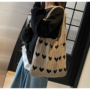 Detalle del bolso tote de punto caqui con corazones negros y textura de lana