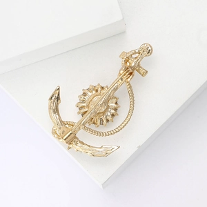 Macro shot of gold alloy nautical anchor brooch featuring helm and rope textures