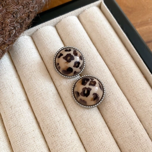 Close-up of leopard print resin earrings with vintage silver beaded metal border detail